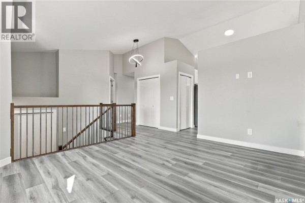 Empty bedroom with beige walls, dark wood flooring, and a bi-fold closet door. - 246 Sutter Place, Saskatoon