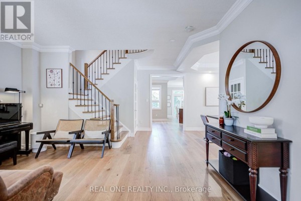 Hallway with light wood floors, a staircase with black spindles, and a console table with a mirror. - 2463 Parkglen Avenue, Oakville