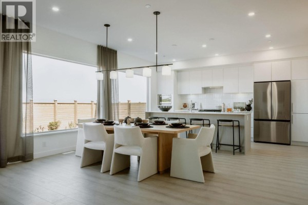 Modern kitchen with white cabinets, an island, and a dining table with chairs. - 2464 Alder Way, Tsawwassen