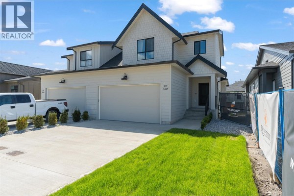 Side view of the duplex home, showcasing a large garage and contemporary architecture. - 2467 Bradley Drive Unit# 102, Armstrong