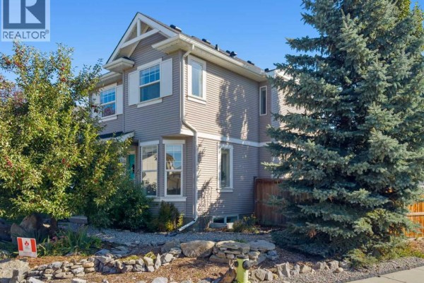 Side exterior of a two-story house with beige siding, bay windows, and mature trees. - 247 Cranberry Place Se, Calgary