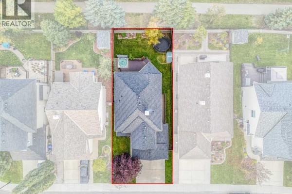 Aerial view of a rectangular lot with a house, backyard, and driveway. - 247 Crystal Shores Drive, Okotoks