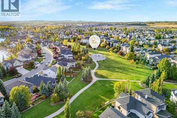 Aerial view of a residential neighborhood with houses, trees, and a park. - 247 Crystal Shores Drive, Okotoks