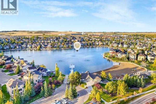 Aerial view of a lakefront community with houses, trees, and a lake. - 247 Crystal Shores Drive, Okotoks