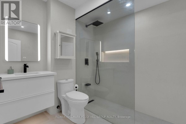 Contemporary bathroom with a floating vanity, toilet, and glass-enclosed shower. - 247 Diana Drive, Orillia