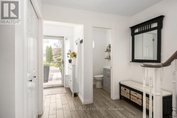 Interior foyer with a view of the front door, a hallway to a powder room, and staircase. - 247 Overbank Drive, Oshawa