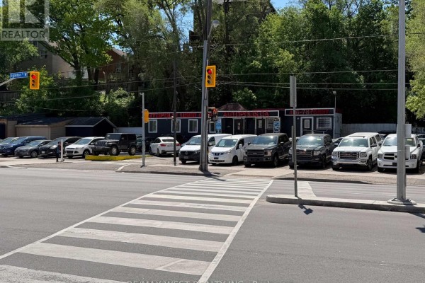 View of a commercial property with a row of vehicles and a pedestrian crosswalk. - 2471-b Eglinton Avenue W, Toronto