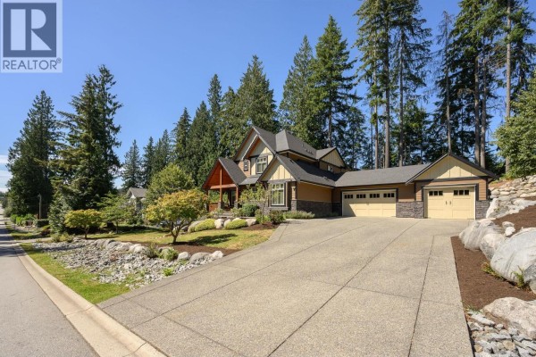 Wide view of the house exterior, driveway, and surrounding trees from the street. - 2475 Leggett Drive, Port Moody