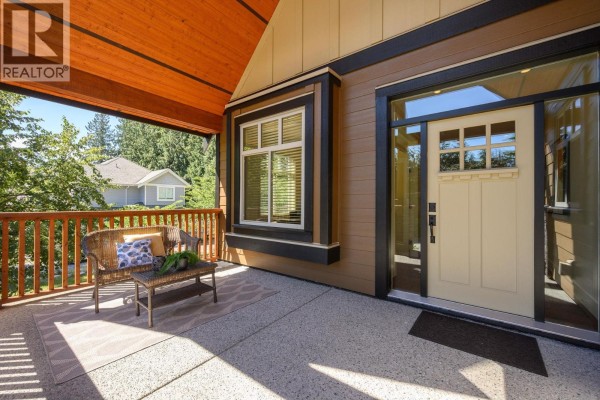 Covered front porch with seating area next to the light beige front door. - 2475 Leggett Drive, Port Moody