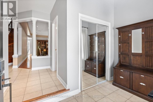 Foyer with tiled floor, mirrored closet, and dark wood furniture against grey walls. - 2476 Palmerston Road, Oakville