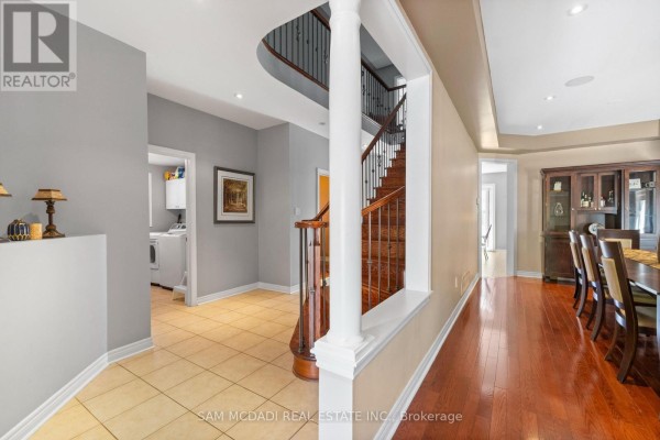 Interior hallway with tiled and wood floors, a staircase, and view into dining room. - 2476 Palmerston Road, Oakville