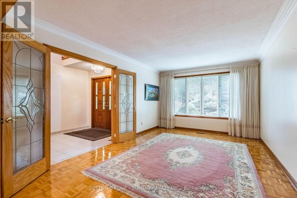 Living room with parquet flooring, a large oriental rug, and a picture window. - 2477 Cliff Road, Mississauga