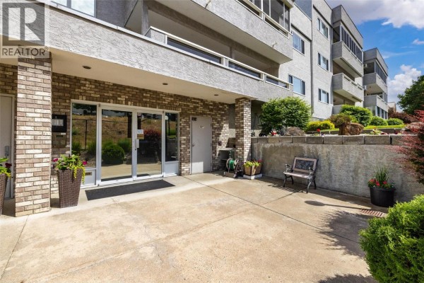 Aerial view of apartment buildings and surrounding neighborhood with mountains and lake in distance. - 2477 Ingram Road Unit# 110, West Kelowna