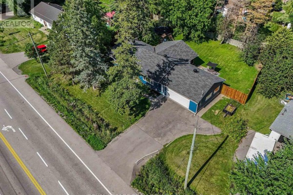 Aerial view of the blue sided bungalow at 2477 Merivale Road with a large driveway. - 2477 Merivale Road, Ottawa