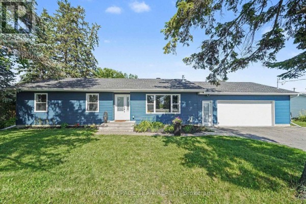 Blue sided bungalow with attached garage and manicured lawn under a twilight sky. - 2477 Merivale Road, Ottawa