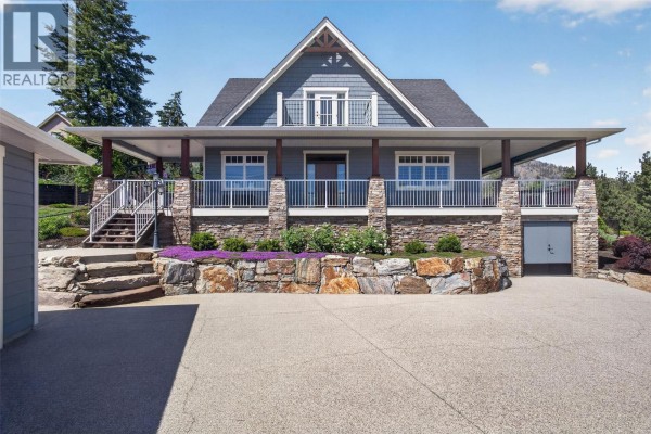 Modern kitchen with dark cherry wood cabinets, granite countertops, stainless steel appliances, and a central island. - 2478 Stone Grove Crescent, West Kelowna