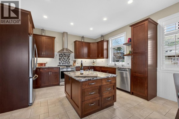 Spacious living room with vaulted ceilings, a loft area, large windows, hardwood floors, and comfortable seating. - 2478 Stone Grove Crescent, West Kelowna