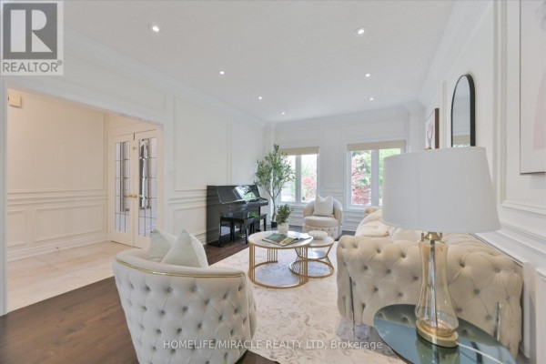 Spacious living room featuring tufted armchairs, a sofa, coffee table, and a black upright piano. - 2479 Rathlin Court, Mississauga