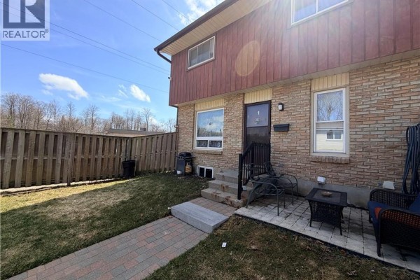 View of the townhouse exterior from the front yard with a brick walkway. - 249 Cedarbrae Avenue Unit# 1, Waterloo