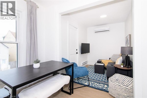 Apartment living area with a blue chair, sofa, coffee table, and patterned rug. - 249 Emerald Street N Unit# 2, Hamilton