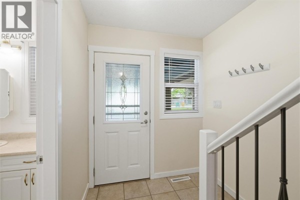 Interior hallway showing wooden stairs with black railing and closet doors. - 249 Kitchener Crescent Unit# 5, Kamloops