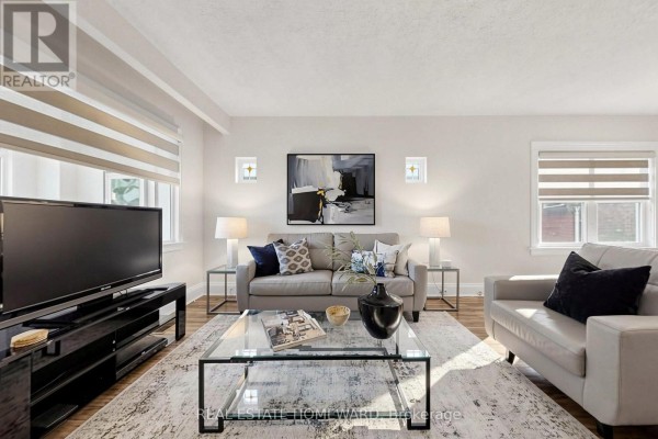Living room facing a large television, featuring a grey sofa, armchair, and plush rug. - 249 Queensdale Avenue, Toronto
