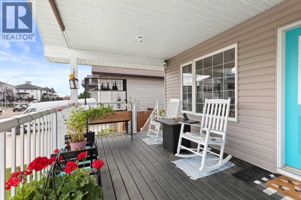 View of a spacious covered porch with rocking chairs, a small table, and plants. - 249 Somerset Way Se, Medicine Hat