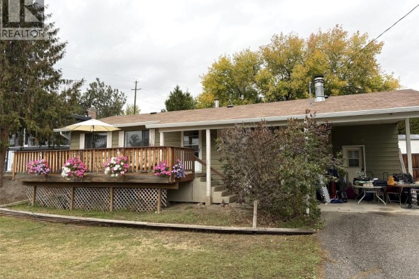 A house with a wood deck, covered carport, and some outdoor storage. - 2490 Smid Road, West Kelowna