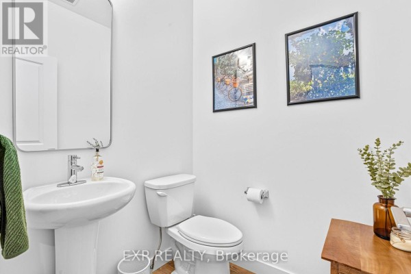 A small powder room with a white pedestal sink, toilet, and wood-look flooring. - 25 - 166 Mount Albion Road, Hamilton