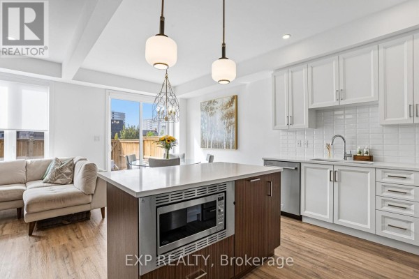 Open concept kitchen and living area with a large island, sectional sofa, and patio door. - 25 - 166 Mount Albion Road, Hamilton