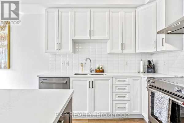 White kitchen cabinets with subway tile backsplash, stainless steel appliances, and a quartz island. - 25 - 166 Mount Albion Road, Hamilton