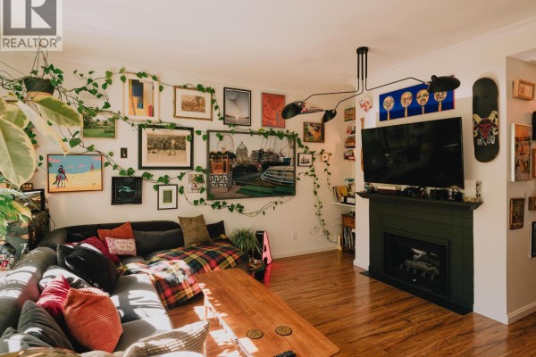 Living room with fireplace, television, large sectional sofa, and wall art. - 25 5988 Hastings Street, Burnaby