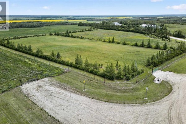 Aerial view of a large, fenced rectangular field surrounded by trees and bordering a gravel road. - 25 713019 Rge Rd 71, Rural Grande Prairie No  1, County Of