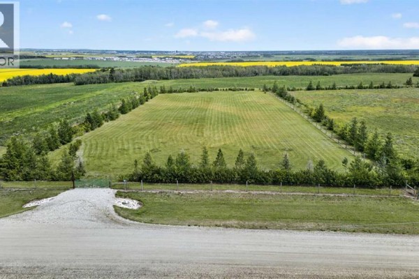 View of a mown, fenced field with a gravel driveway leading to a green gate and surrounding landscape. - 25 713019 Rge Rd 71, Rural Grande Prairie No  1, County Of