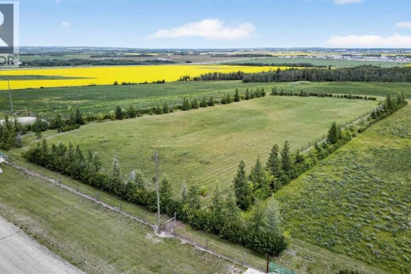 Aerial perspective of a long, fenced rectangular field bordered by trees and rural landscape with yellow fields beyond. - 25 713019 Rge Rd 71, Rural Grande Prairie No  1, County Of