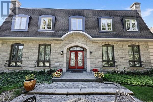 Front entrance with double red doors, stone exterior, and manicured landscaping. - 25 Bovair Trail, Aurora