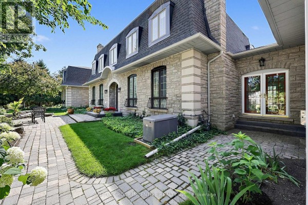 Paved walkway leading past the stone exterior of the house with green landscaping. - 25 Bovair Trail, Aurora