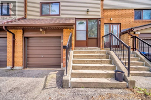 Close-up of townhouse entrance with concrete stairs, brown garage door, and white front door. - 25 Carleton Place, Brampton