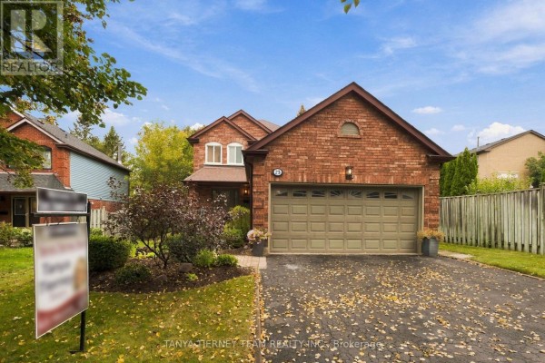 Front exterior of a brick house with a large garage and a paved walkway to the entrance. - 25 Coulton Court, Whitby