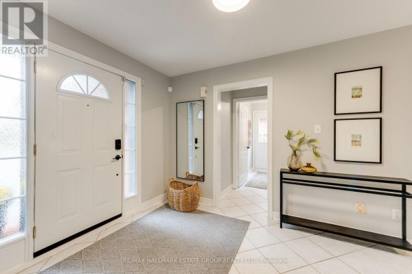 Foyer with white door, tiled floor, grey rug, full-length mirror, and console table. - 25 Dewbourne Place, Whitby