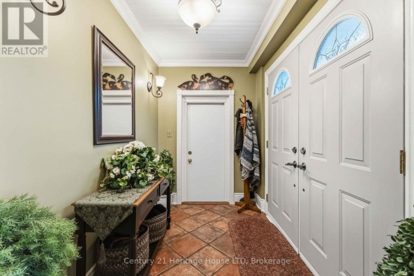 Foyer with light green walls, terracotta tile floor, view of stairs, and double doors. - 25 Glenview Avenue, Welland