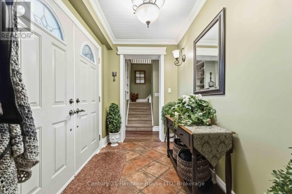 Living room with tan walls, wood floors, bay window, sofas, armchairs, and bookshelves. - 25 Glenview Avenue, Welland