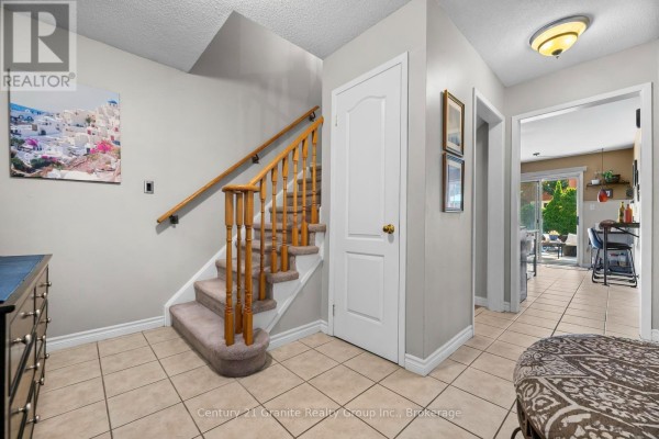 Foyer with a carpeted staircase, tiled floor, and doorway to the kitchen. - 25 Greenwood Road, Whitchurch Stouffville