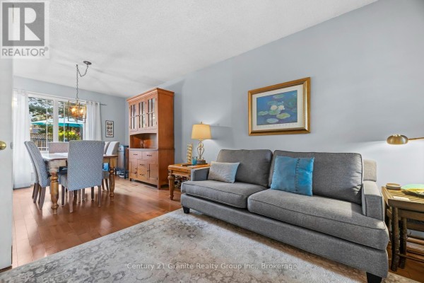 Living room with a grey sofa, wooden furniture, dining set, and hardwood floors. - 25 Greenwood Road, Whitchurch Stouffville