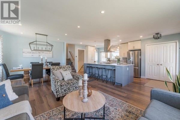 Open concept living, dining, and kitchen area with light blue walls and wood floors. - 25 Hewson Drive, Port Hope