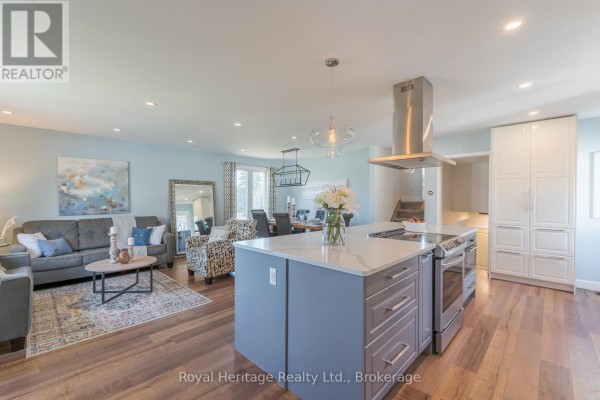 Kitchen with stainless steel appliances, white cabinets, and stairs leading to the basement. - 25 Hewson Drive, Port Hope