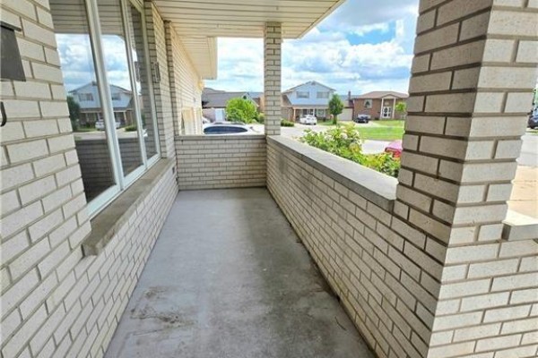 Covered porch with light beige brick pillars and a concrete floor overlooking the street. - 25 Highfield Avenue Unit# Upper Level, St  Catharines