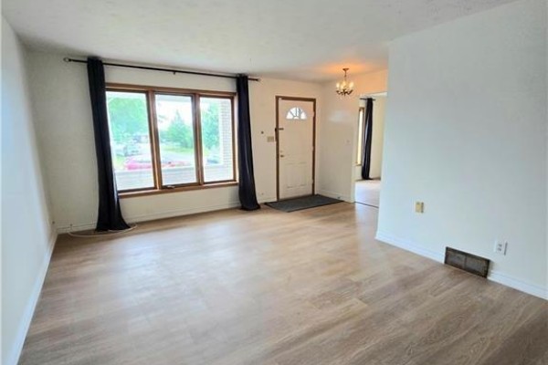 Living room facing the front entrance, featuring a sofa, armchair, and large windows. - 25 Highfield Avenue Unit# Upper Level, St  Catharines