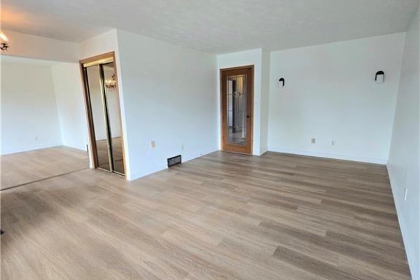 Spacious living and dining area with light wood laminate flooring and white walls. - 25 Highfield Avenue Unit# Upper Level, St  Catharines