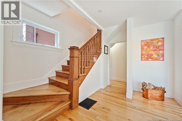 Interior view of a wooden staircase and hallway with light wood floors and white walls. - 25 Hillcrest Drive, Moncton